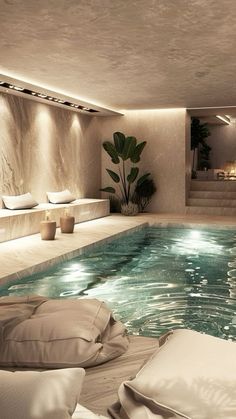 an indoor swimming pool with lounge chairs and pillows on the floor, next to it