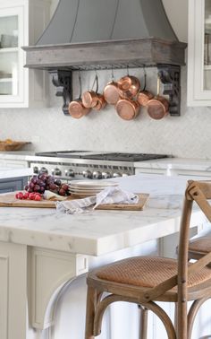 a kitchen with an island and copper pots hanging from the ceiling over the stove top