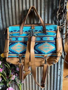 The Mojave Sky Diaper Bag is inspired by the desert sky. This bright turquoise and blue woven serape collection creates an irresistible appeal that is accented by classic aztec patterns and hand distressed full grain leather. Features Woven serape with aztec patterns Full grain leather accents Removable leather shoulder straps Leather handles for easy carrying Removable and adjustable nylon shoulder strap Zip top closure for keeping everything secure 1 interior zip closure pocket 2 exterior slip pockets Concealed carry pocket Branded STS leather patch 16.5" W x 13" H x 6" D Desert Sky, Bright Turquoise, Leather Accents, Aztec Pattern, Leather Handles, Leather Patches, The Desert, Zip Top, Full Grain Leather