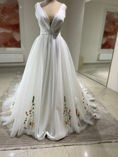 a white wedding dress on display in a room with tile flooring and wallpaper