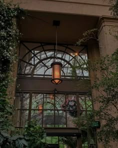 the inside of a building with an iron and glass entrance way, surrounded by greenery