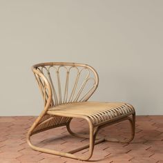 a wicker chair sitting on top of a brick floor next to a wall in an empty room