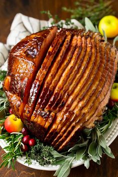 the best ham glaze recipe on a platter with apples and cranberries