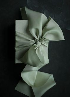 a folded napkin with a large bow on the front and side, sitting on a black surface