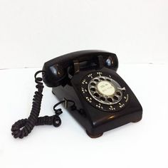 an old fashioned black telephone on a white surface