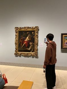 a person taking a picture of a painting on display in an art gallery with other people looking at it