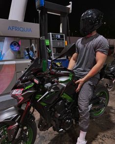 a man sitting on top of a motorcycle next to a gas pump at night time