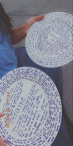 two plates with words written on them are being held by someone's hand while sitting down