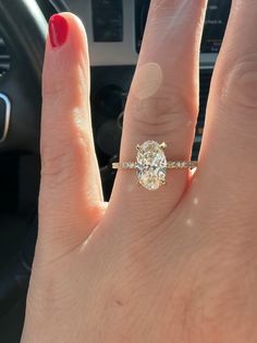 a woman's hand with a ring on it and a car steering wheel in the background