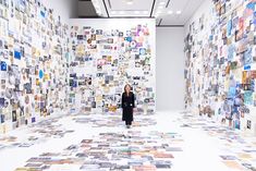 a woman standing in front of a wall covered with pictures