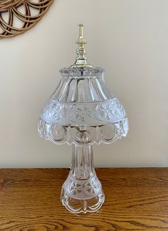 a glass table lamp sitting on top of a wooden table