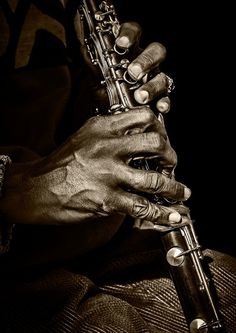 a close up of a person holding a flute in their hands and playing it with both hands