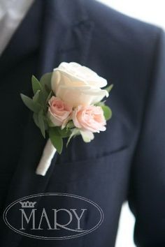 a boutonniere with pink roses and greenery is worn by a man in a suit