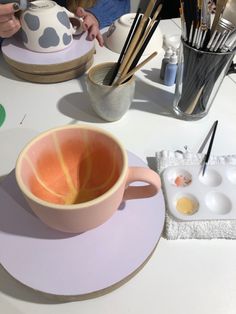 a cup with an orange inside sits on a table next to other dishes and utensils