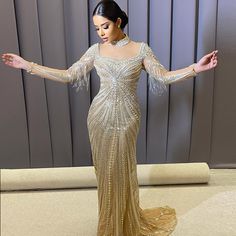 a woman in a gold dress with her arms outstretched