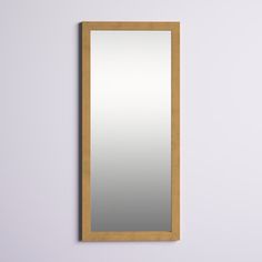 a mirror mounted to the side of a wall next to a wooden frame on a white wall