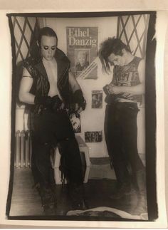 an old black and white photo of two men in leather outfits standing next to each other