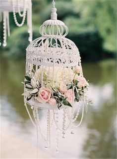 a white birdcage with flowers hanging from it's sides on a postcard