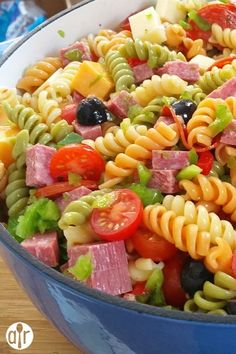 a blue bowl filled with pasta salad on top of a wooden table