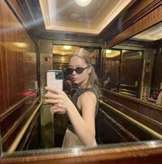 a woman taking a selfie in front of a mirror on a train with her cell phone