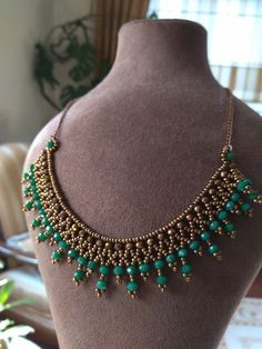 a gold and green beaded necklace on a mannequin's neckline