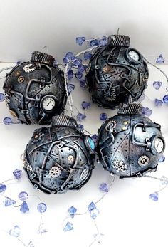 four pieces of art made out of metal and blue glass beads on a white surface