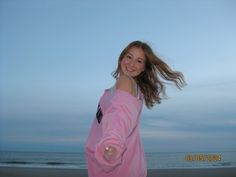 a girl in a pink sweatshirt pointing at the camera