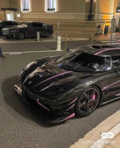 a black sports car with pink stripes parked on the street