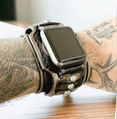 Check out this awesome vintage-looking distressed black leather cuff made for your Apple Watch! It's rugged, with antique silver rivets and made from high-quality full-grain leather. The 2-inch wide band is handcrafted in the USA, ensuring the best quality for your wrist! Each item is handmade and designed by Cuckoo Nest Art Studio™. The watch bands made from vegetable tanned leather what is known as the highest quality leather available and used for high-end handmade leather goods. Usually, this kind of leather is stiff in the beginning however, it does get wonderfully soft and pliant over time. Vegetable tanned leather provides great value for money due to its durability and never goes out of style. MADE IN USA CUCKOO NEST ART STUDIO™ DESIGN  This listing is for the WATCH STRAP BAND + co Vintage Leather Apple Watch Band With Bracelet Strap, Vintage Leather Bracelet Strap For Apple Watch, Vintage Adjustable Bracelet Strap Apple Watch Band, Adjustable Vintage Bracelet Strap Apple Watch Band, Vintage Silver Leather Watch Accessories, Vintage Black Adjustable Watch Bands, Vintage Silver Leather Bracelet, Vintage Leather Bracelet With Custom Hardware, Apple Watch Cuff