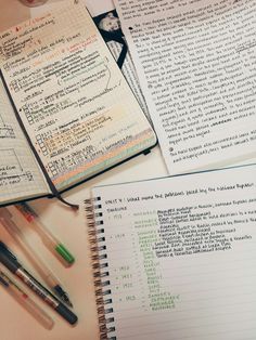 several notebooks and pens sitting on top of each other next to an open book