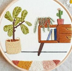 an embroidery project with plants and books on it