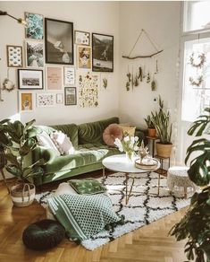 a living room filled with lots of plants and pictures on the wall above it's couch