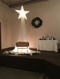 a stage set up for a wedding with a star on the wall and wreaths around it