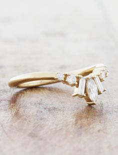 a yellow gold ring with three white stones on the top and one diamond in the middle