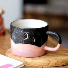 a pink and black coffee cup sitting on top of a wooden table