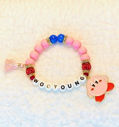 "For all the KirbyWoo enthusiasts! This adorable Wooyoung Pink matte glass and Genuine Blue Agate beaded bracelet is paired with red pavé and gold and rhinestone accents, with mini tassel and cute Kirby charm. Letters are printed porcelain- NO PLASTIC. Sizes are approximate based on bead size, can vary within 1/8-1/4\"." Cute Kirby, Rose Quartz Bracelet Beads, Rose Quartz Beads, Glass Beaded Bracelets, Blue Agate, Agate Beads, Kirby, Arm Band, Beaded Bracelet