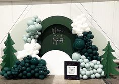 an arch made out of balloons with trees on the front and back, surrounded by other decorations