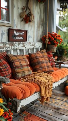 a porch swing with pillows and pumpkins on it