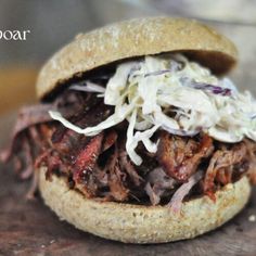 a close up of a sandwich with meat and coleslaw on it's bun