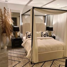 a four poster bed in a bedroom with black and white decor