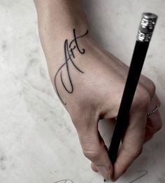 a person's hand holding a black pen with the word faith on it