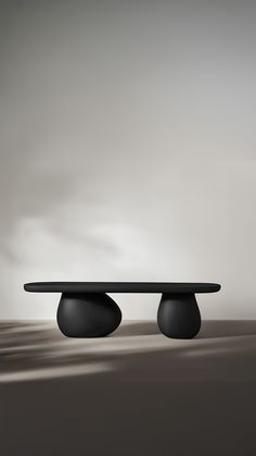 a black table sitting on top of a floor next to a white wall with clouds in the background