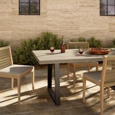 an outdoor table with chairs and a bottle of wine on it