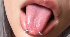 a woman sticking her tongue out with some piercings on it