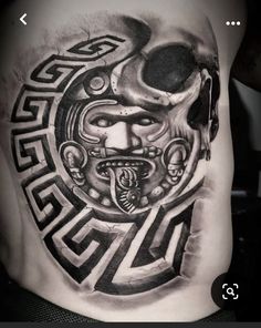 a man's back with a tattoo design on his stomach and an image of a mask