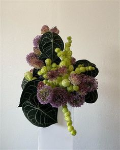 a white vase filled with purple and green flowers