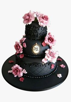 a three tiered black cake with pink flowers on the top and bottom layer,