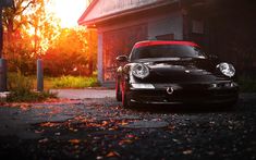 a black car parked in front of a building with the sun shining down on it