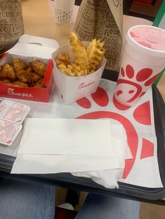 a tray with some food on it and two cups of drink next to it sitting on a table