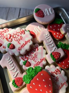 some decorated cookies are sitting on a cookie sheet in the shape of strawberrys and letters